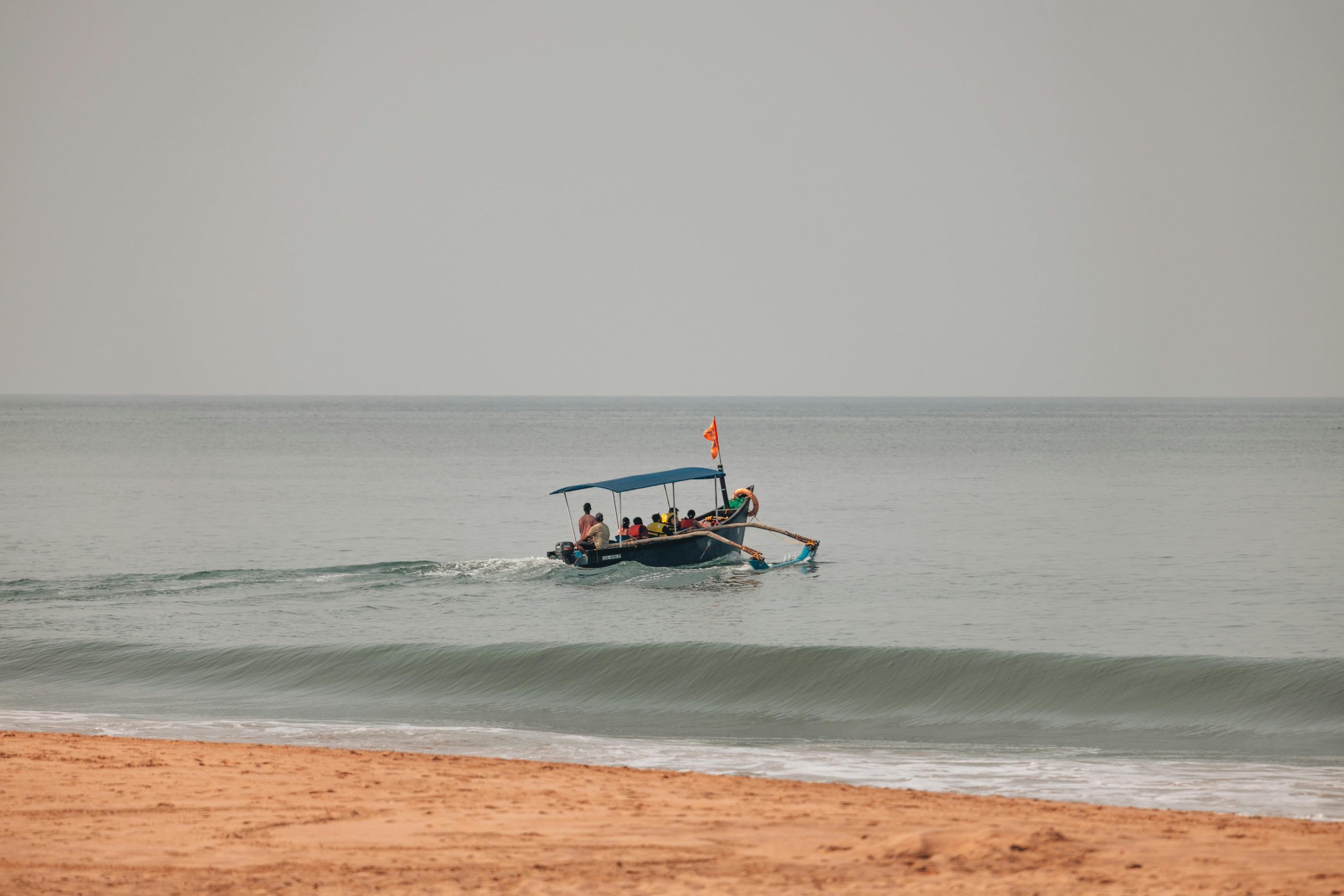 A peaceful beach setting with a boat gently gliding on calm ocean waters.